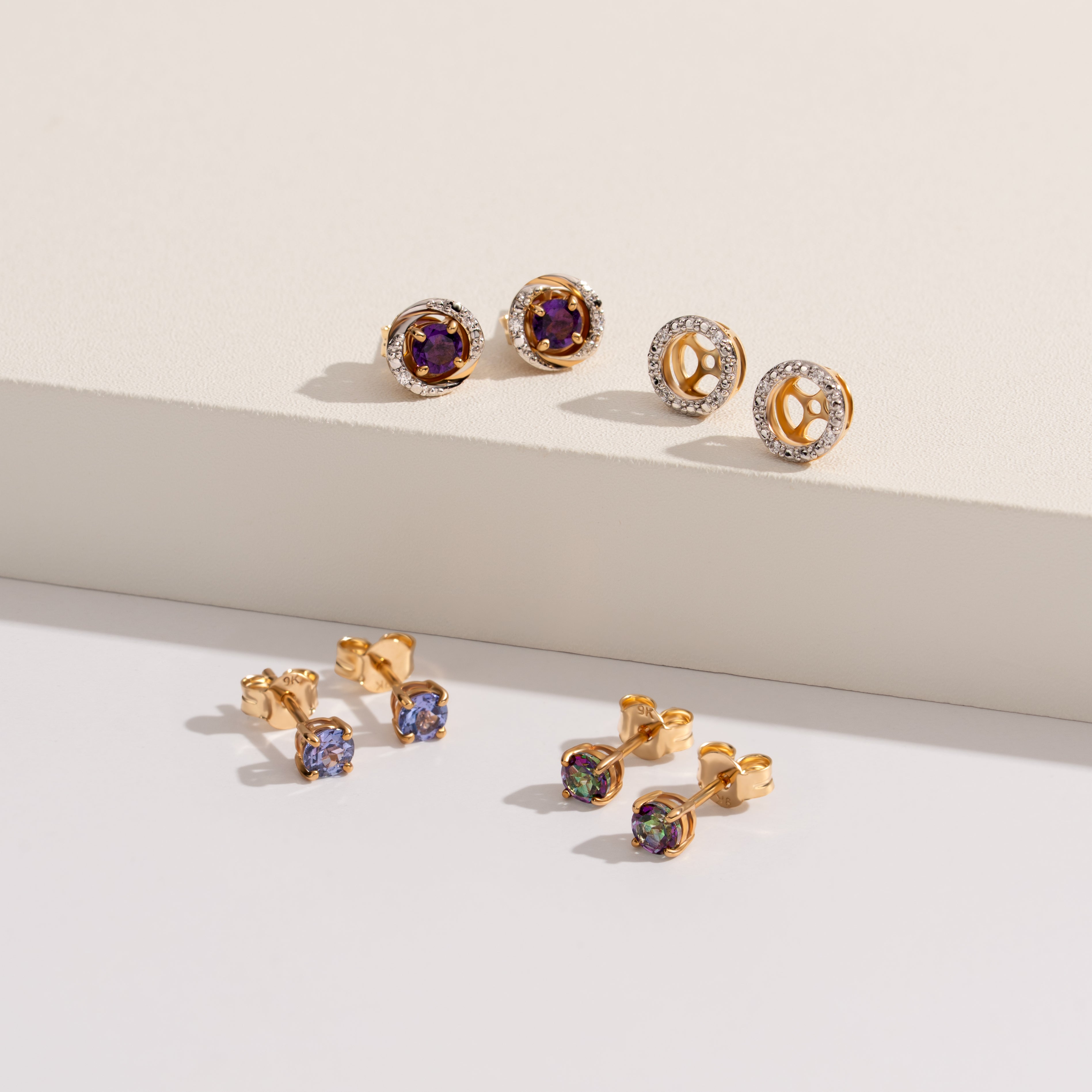 Gold earrings with gemstones on a light background